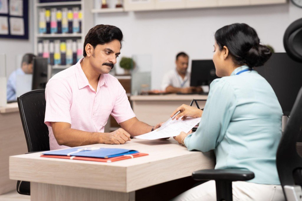 A man and a woman reviewing application papers across an office desk.
