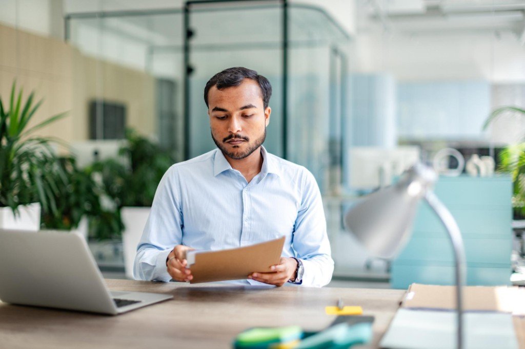 A man reviewing documents at an office desk.