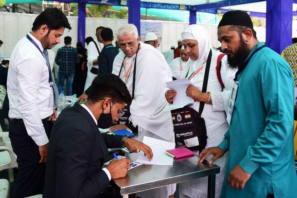 Pilgrims reviewing Haj application papers with staff at a Haj Committee of India counter.